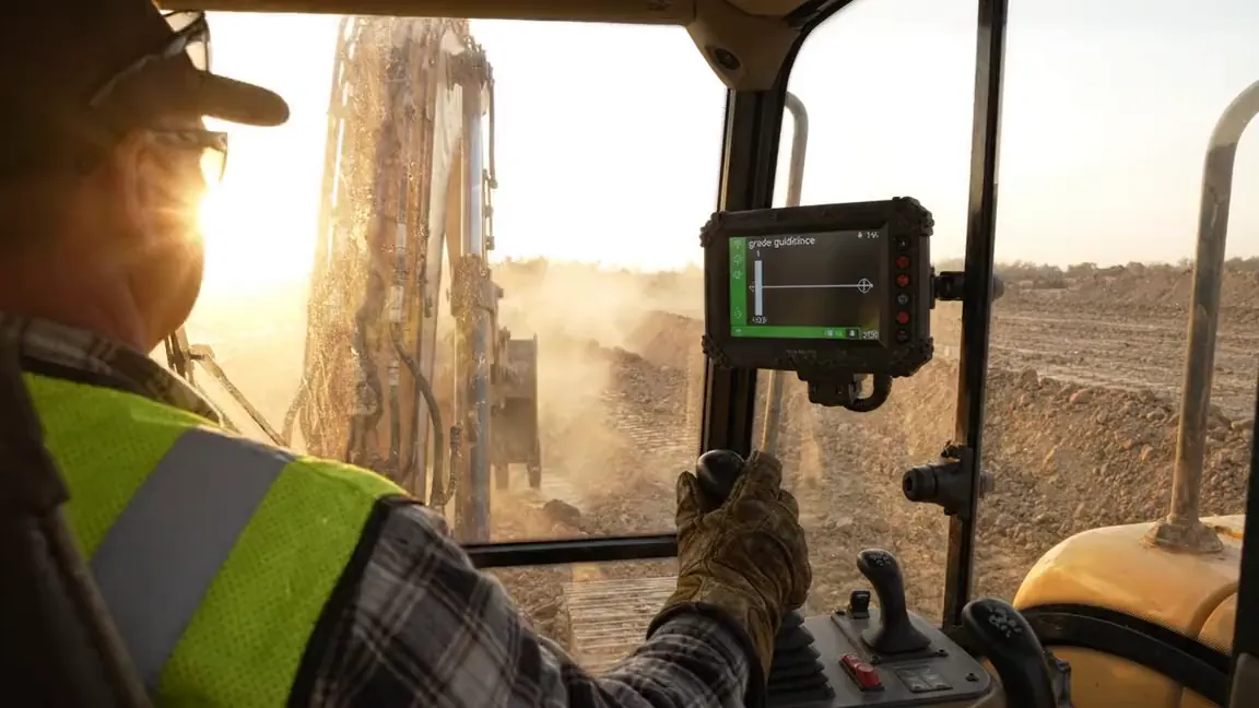 Operator working a dozer with a grade control display mounted in the cab